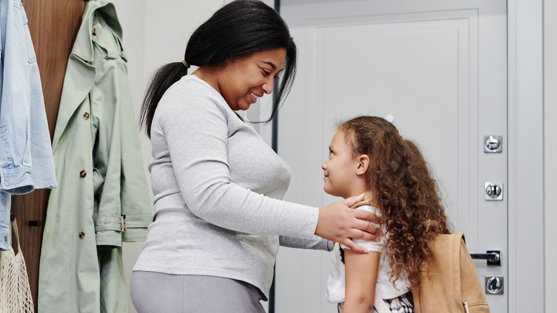 A joyful mother and daughter sharing a moment before the child's school day indoors.