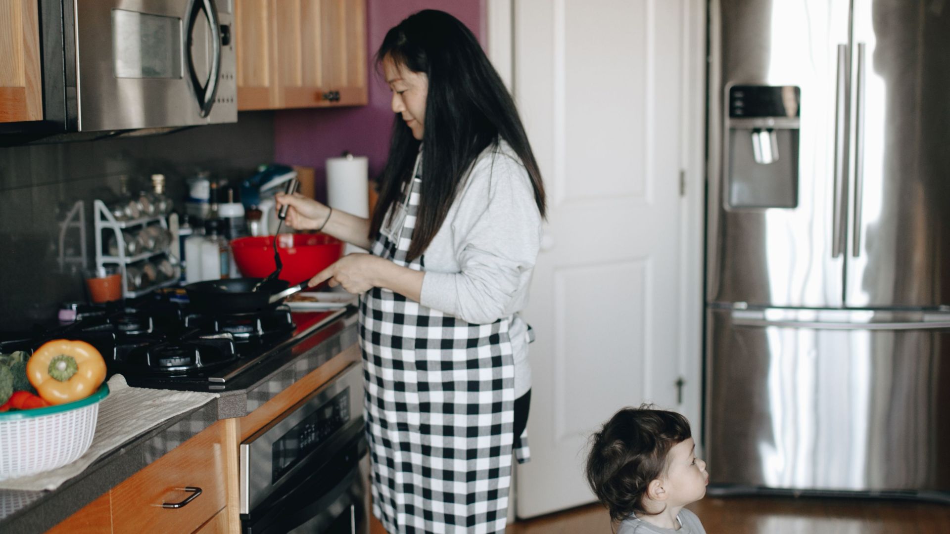 A mother and child enjoy cooking together in a cozy home kitchen.