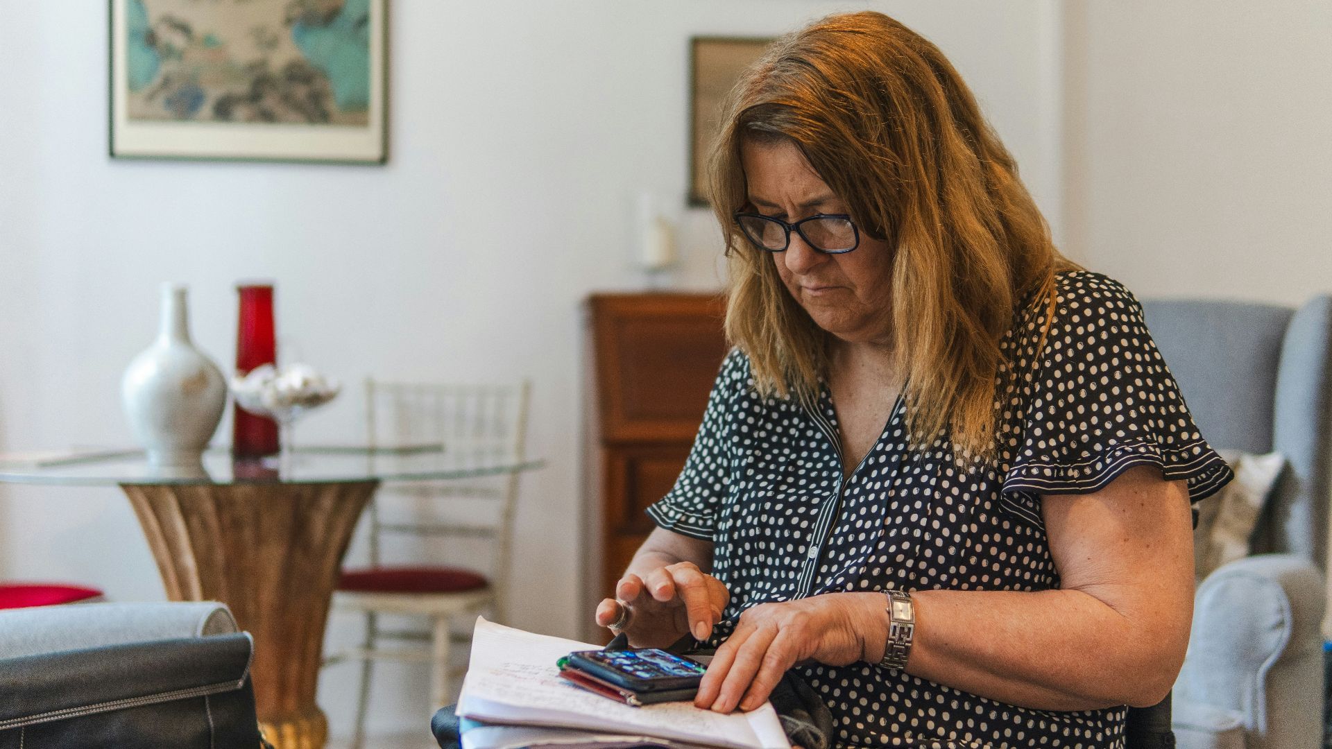 Woman using calculator with papers on table