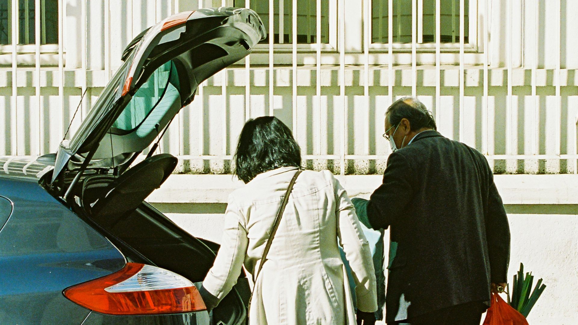 man and woman standing beside black car during daytime