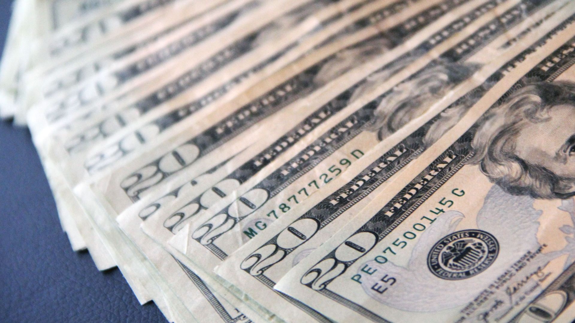 Close-up shot of multiple US twenty dollar bills spread out, symbolizing wealth and finance.