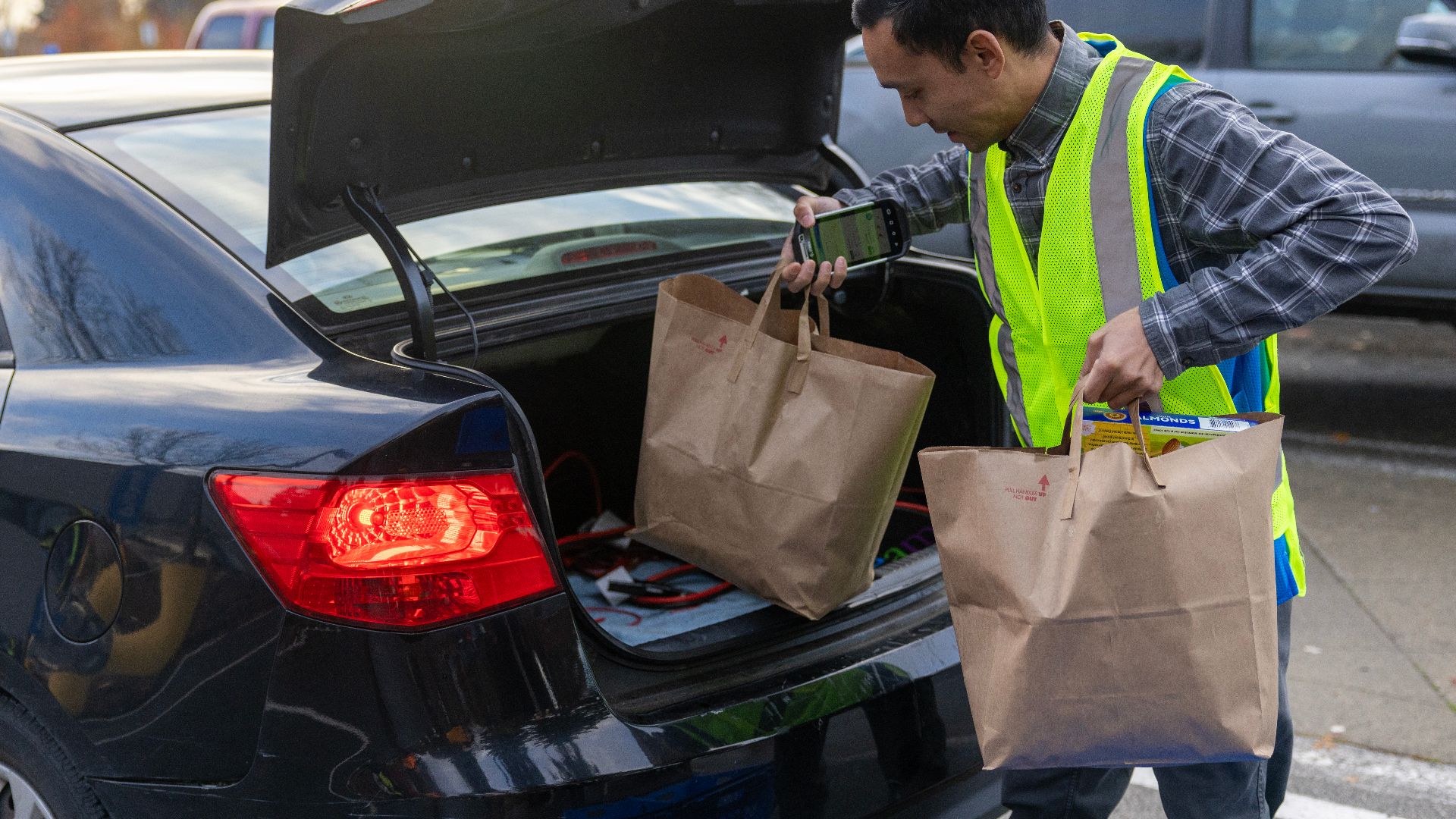 Grocery store staff member puts grocery bags from a fulfilled online order in a WIC parent's trunk of their vehicle at a grocery store in Seattle, WA. (September 2024).