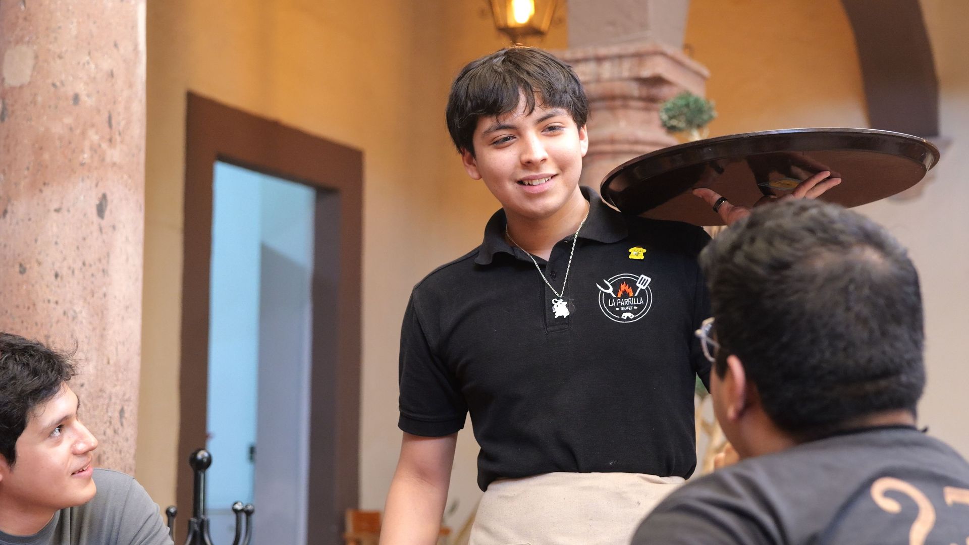 A cheerful waiter interacting with customers at a restaurant in Guanajuato, Mexico.