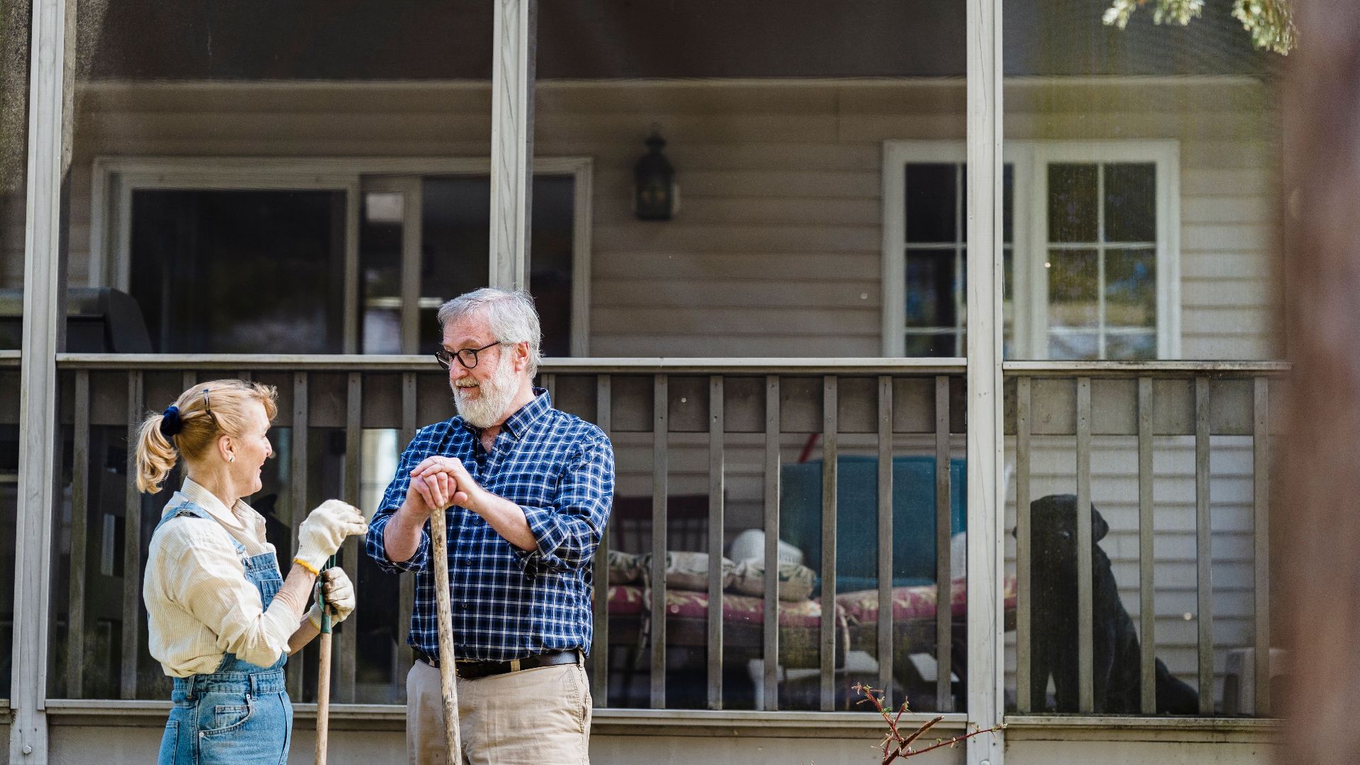 Senior couple gardening outside their home, enjoying a sunny day together.