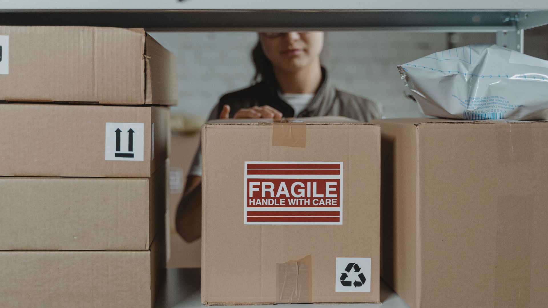 A person organizing fragile cardboard boxes in a warehouse setting.