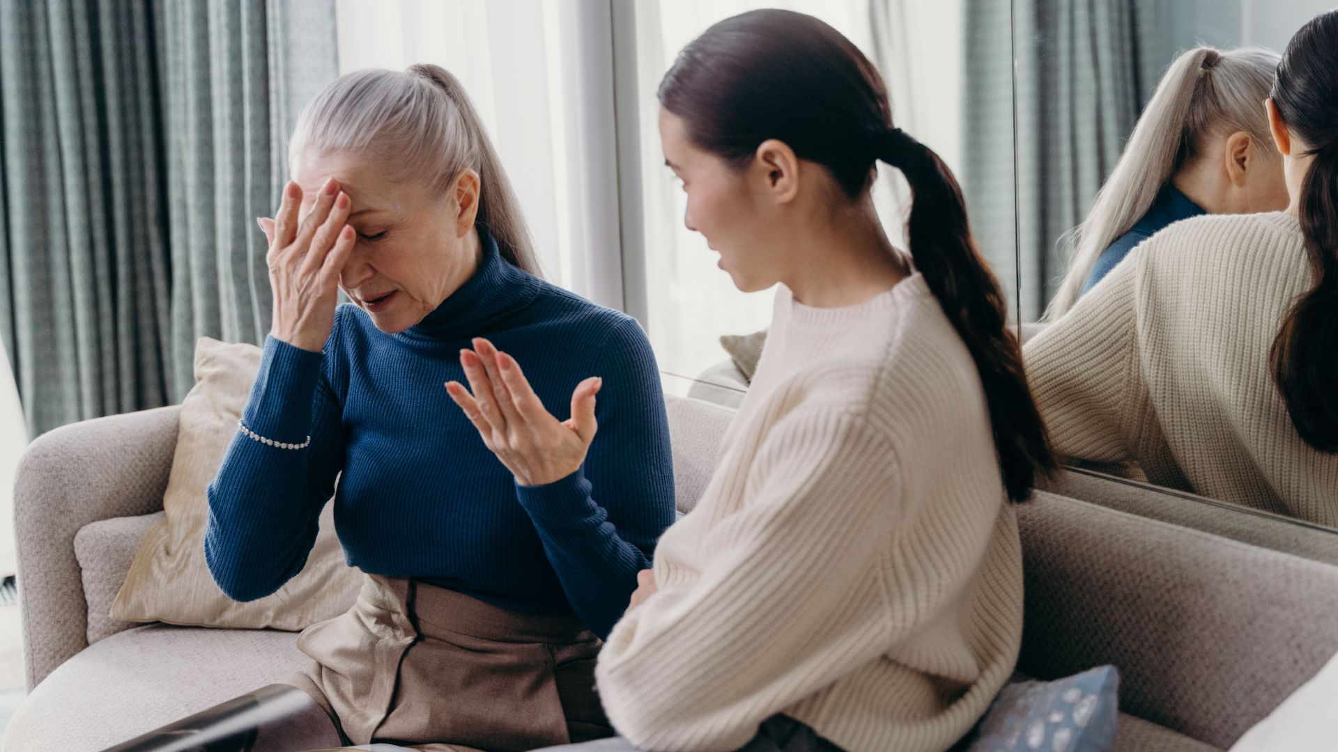 A touching moment of bonding between a mother and daughter sitting on a couch indoors.