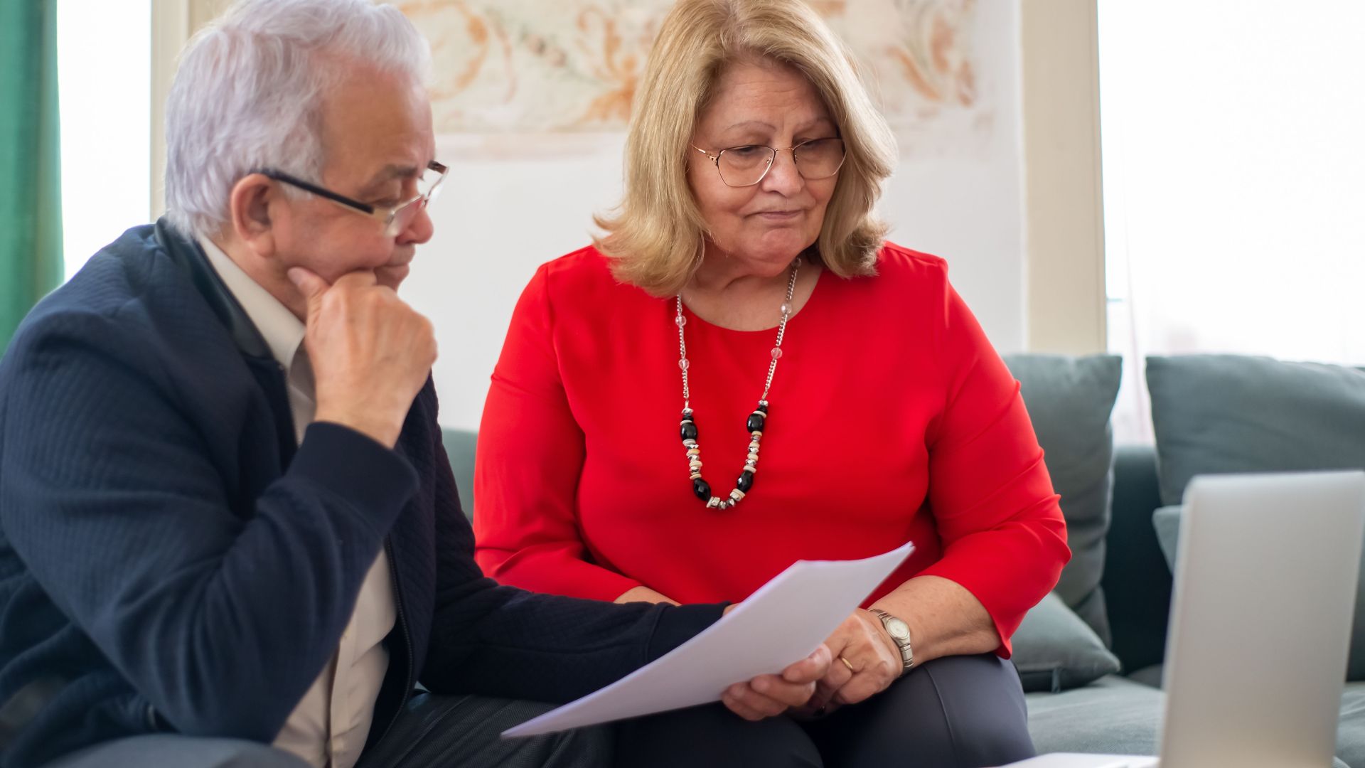 Elderly couple reviewing financial documents together at home in Portugal.
