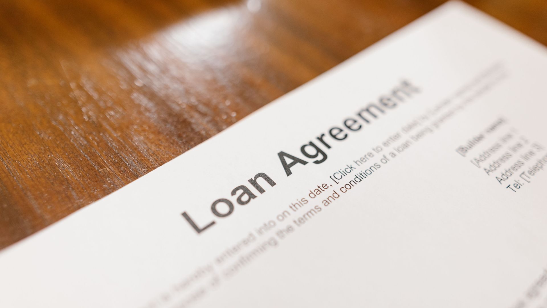Detailed loan agreement document close-up on a wooden table representing legal and financial concepts.