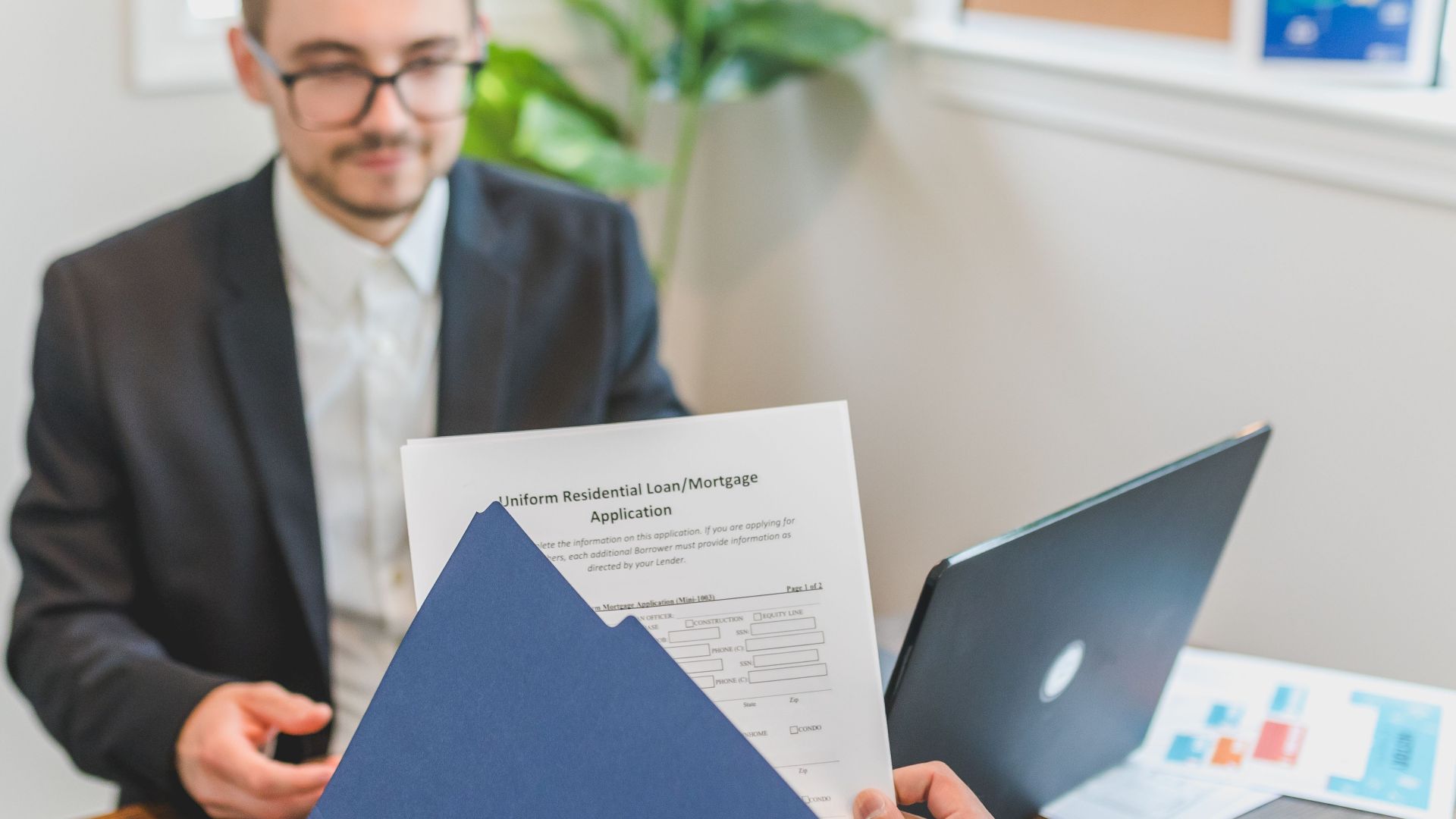 Mortgage broker and client discussing loan application with documents on table.