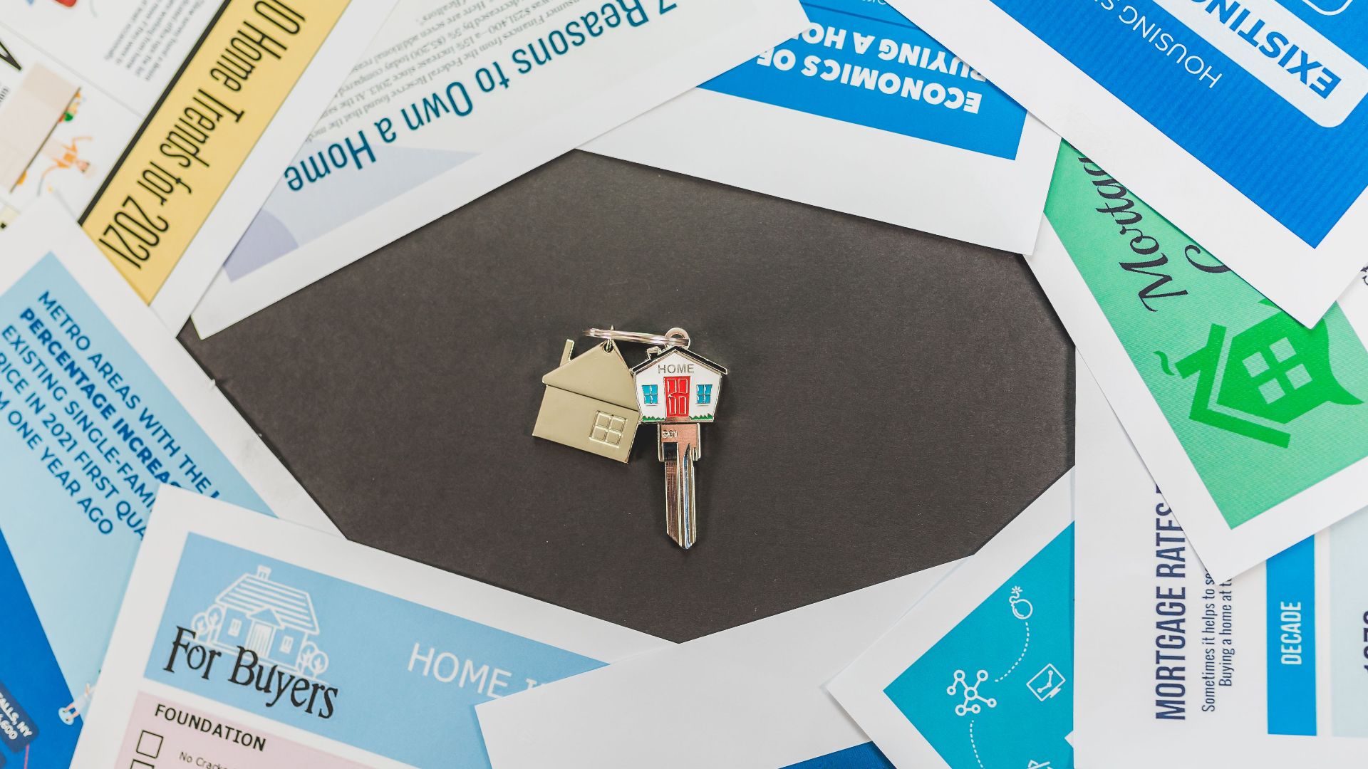 Overhead view of real estate brochures and house key, ideal for marketing.