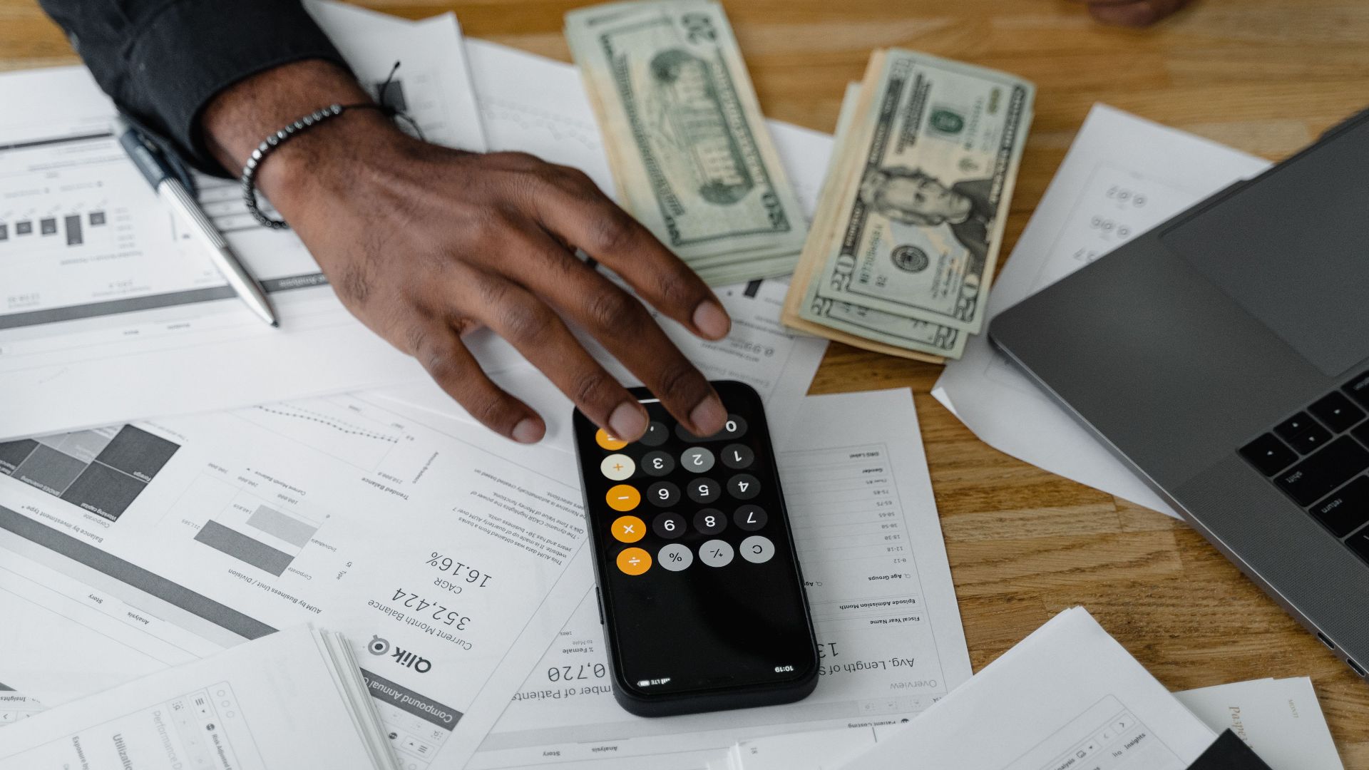 Overhead view of financial documents with calculator, cash, and laptop for financial planning.