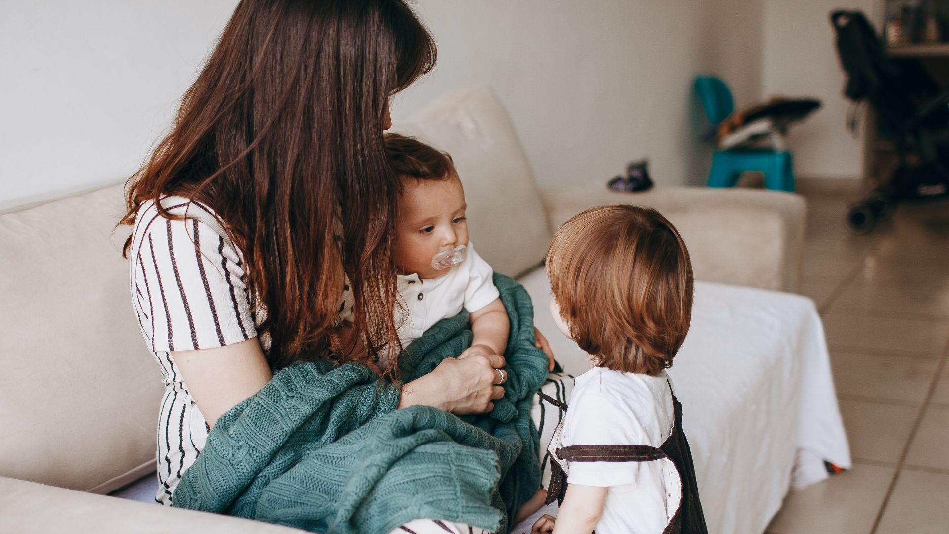 Mother and children share a warm moment on the sofa, filled with love and togetherness.
