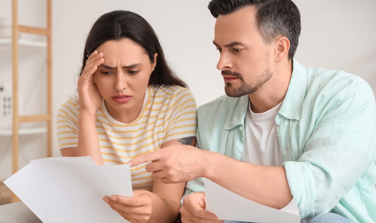Upset young couple looking through documents at home. Bankruptcy concept
