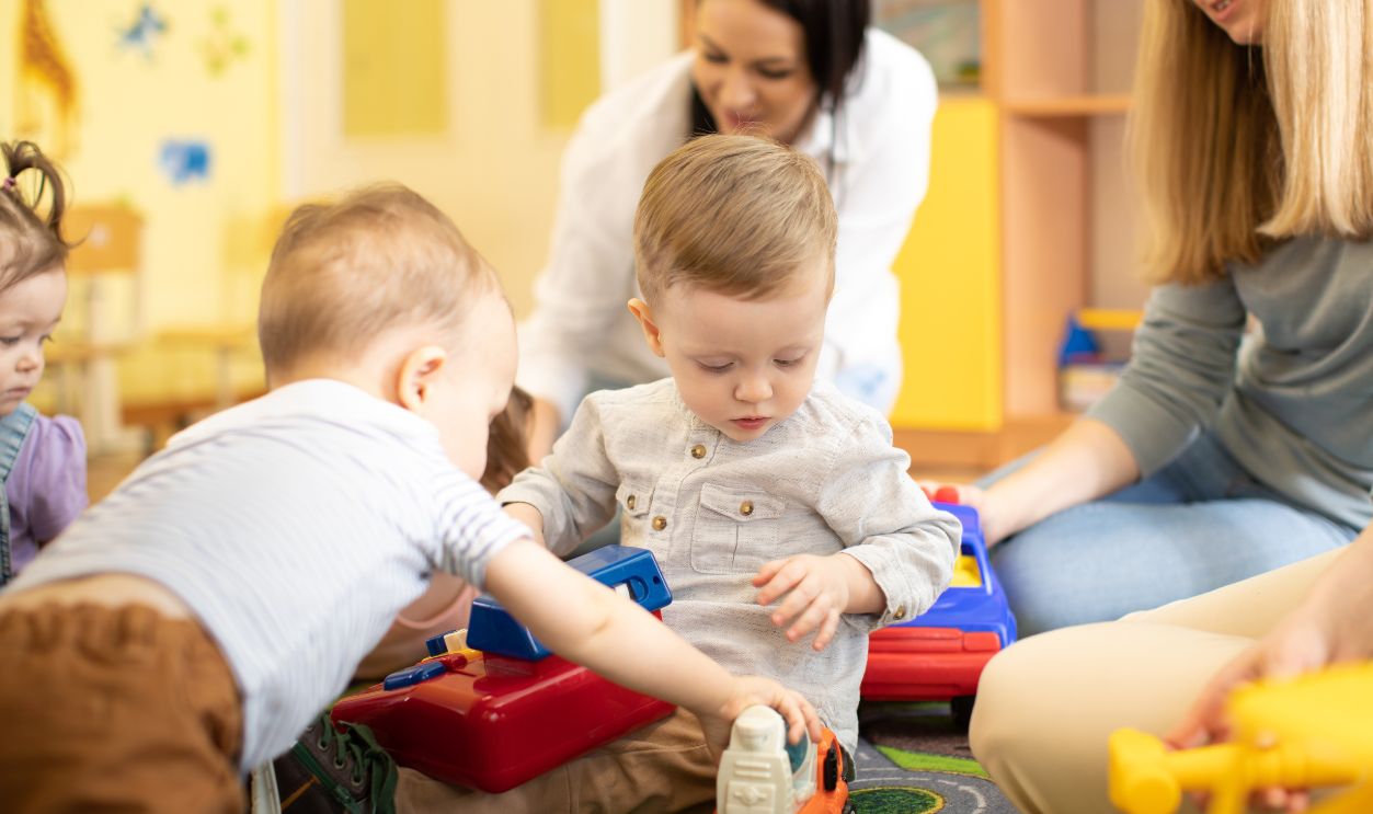 Nursery babies play together with moms in a play room
