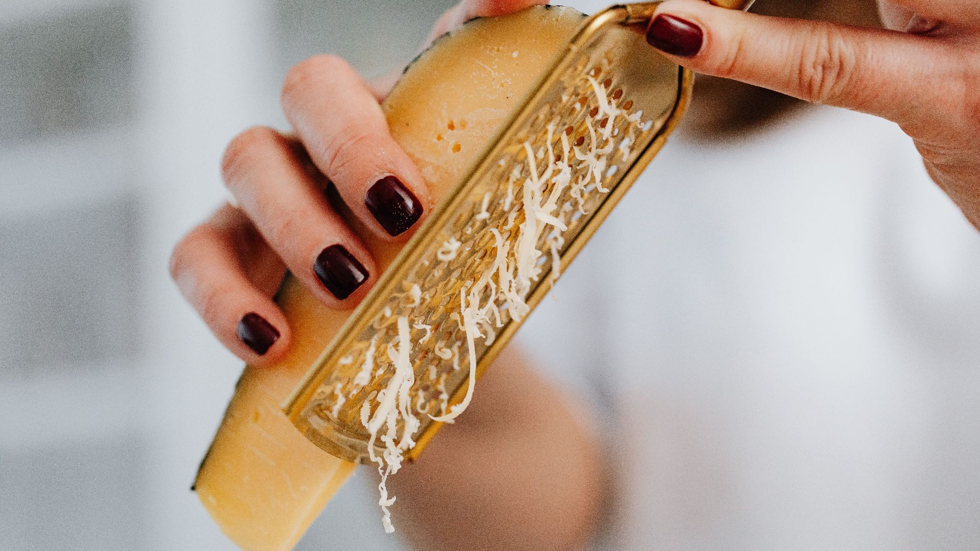 Close-up image of grated parmesan cheese with focus on hands and food preparation.