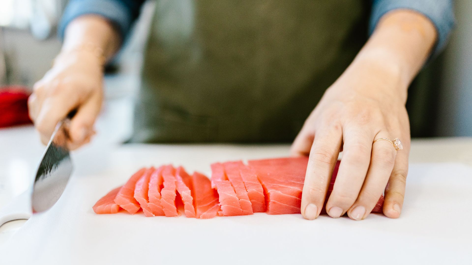 Close-up of hands slicing fresh salmon fillet on a cutting board, ideal for seafood and cooking content.