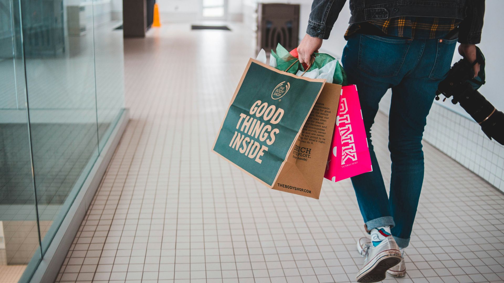 person walking while carrying a camera and paper bags