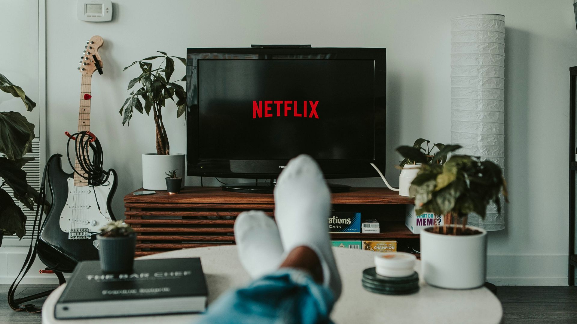 A person with feet in white socks resting on a table before a television