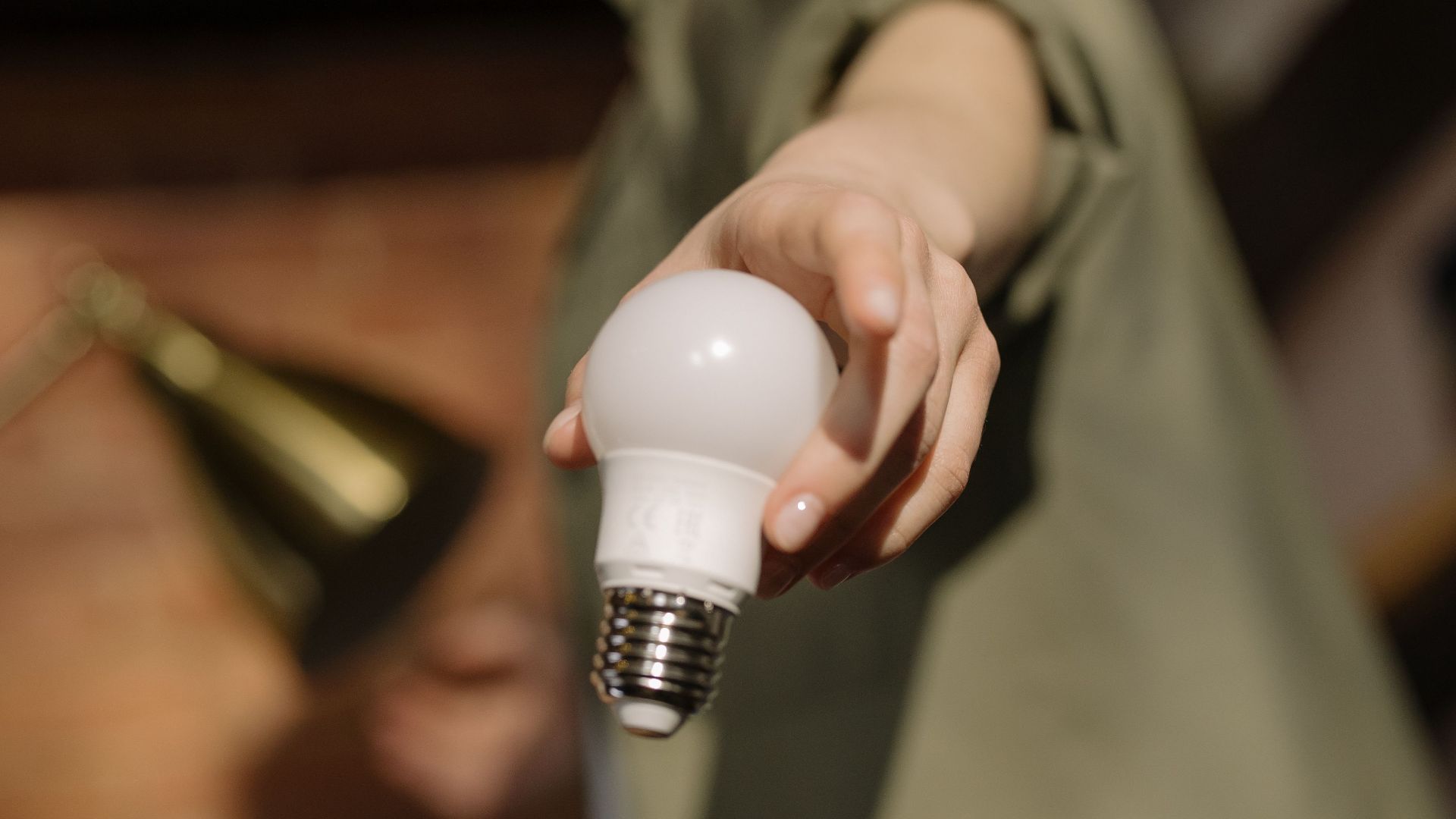 Close-up of a hand holding an LED light bulb indoors, symbolizing energy efficiency and modern home living.