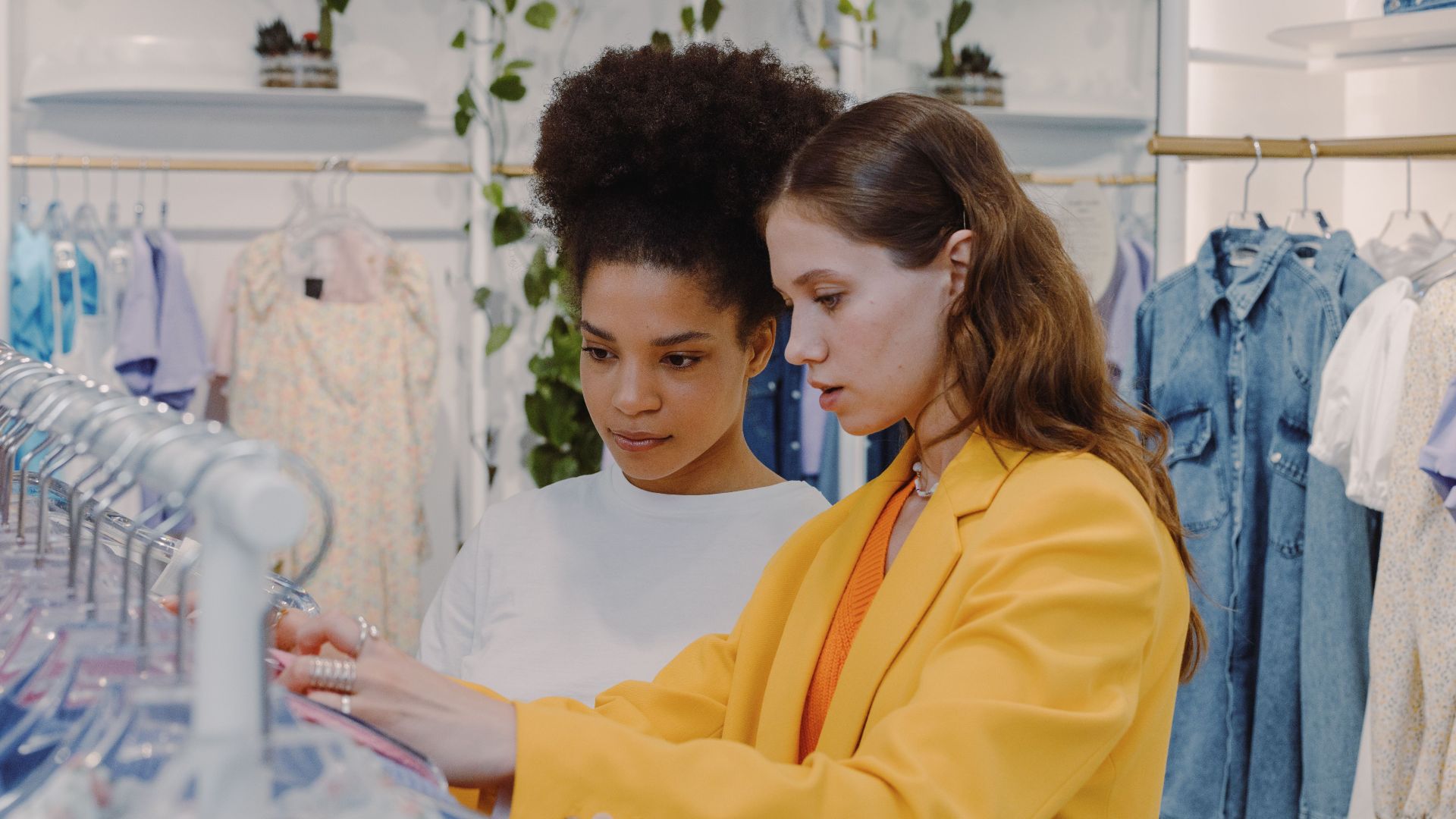 Stylish women shopping and choosing outfits in a modern boutique setting.