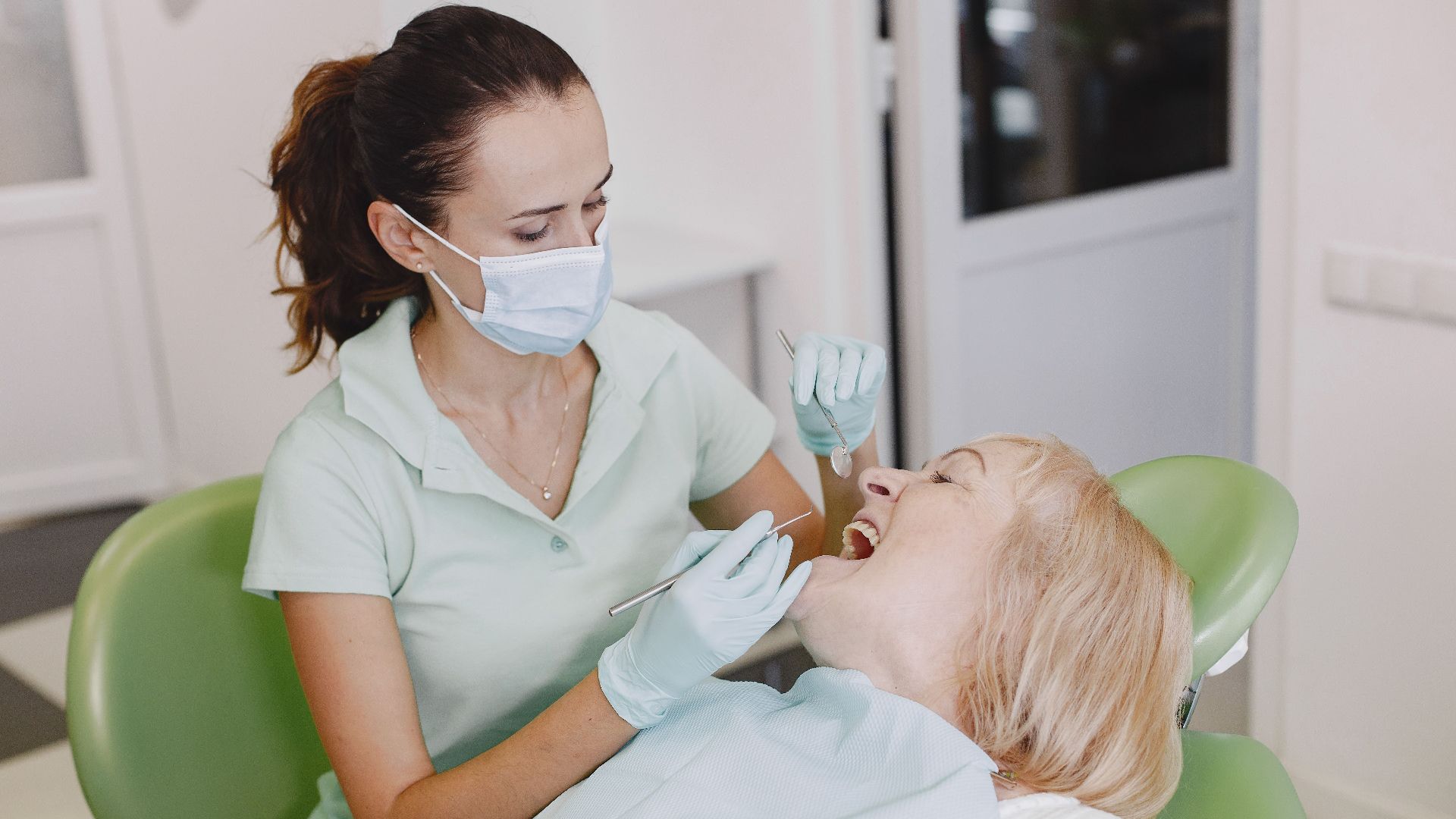 A female dentist examines a patient in a dental office, highlighting professional dental care.