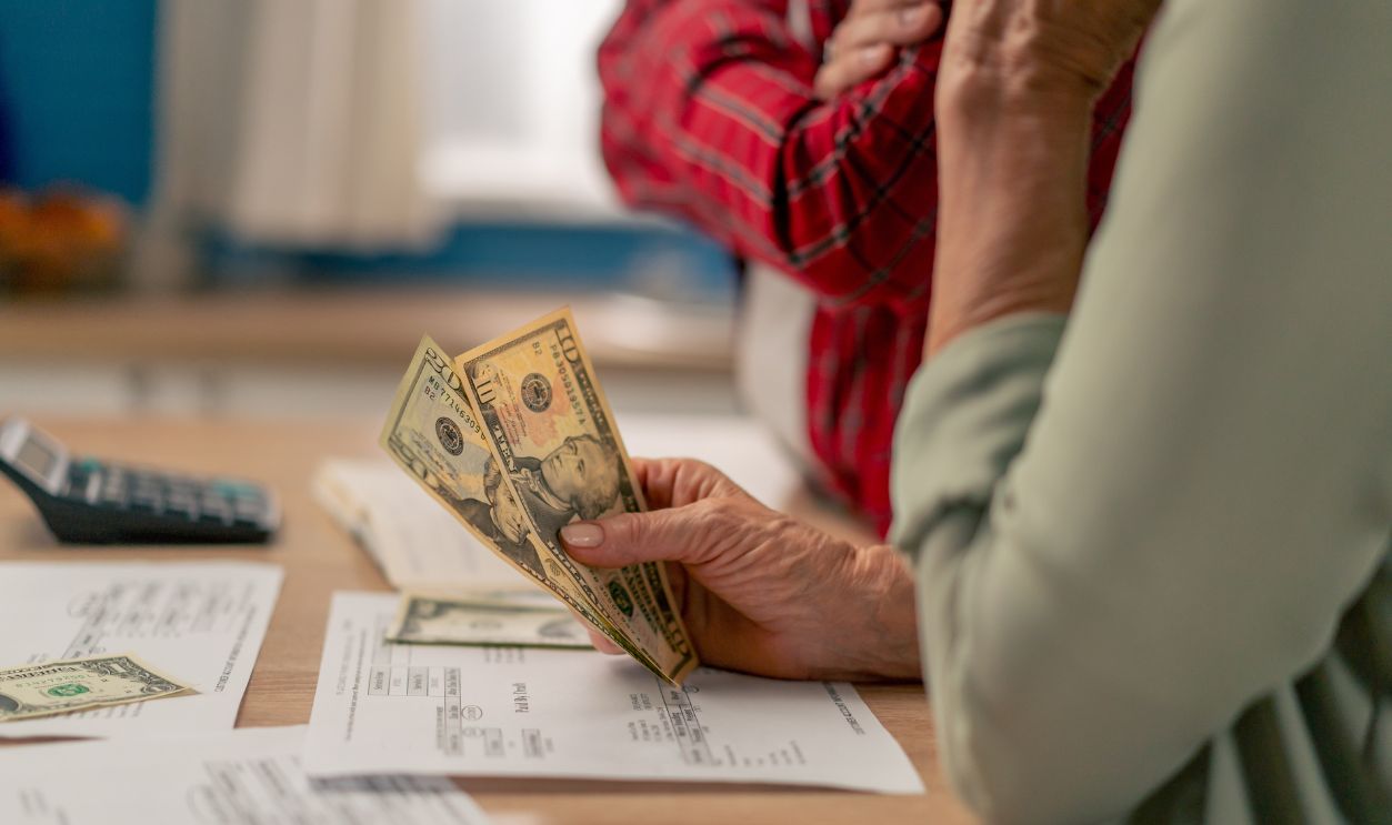 close-up in bright kitchen hands with American bills calculator payment receipts calculator hard pension utilities