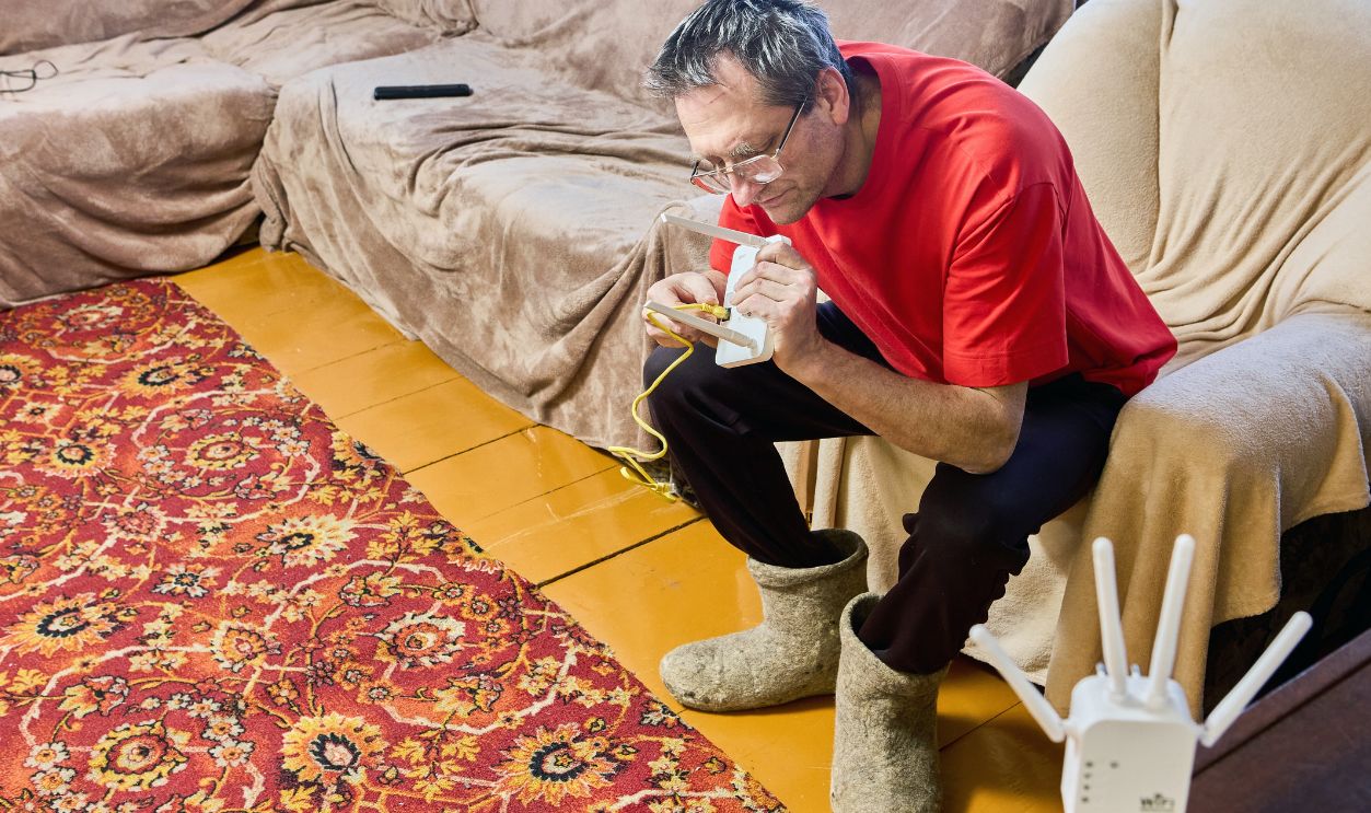Elderly man adjusts router for wifi signal distribution in rural house.