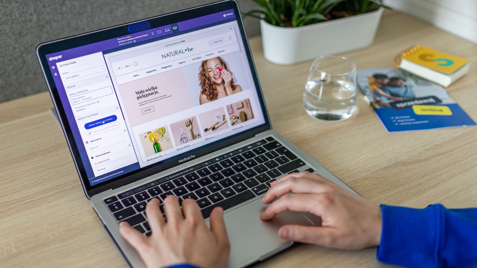 Hands typing on a laptop showing an e-commerce website in a modern office setting.