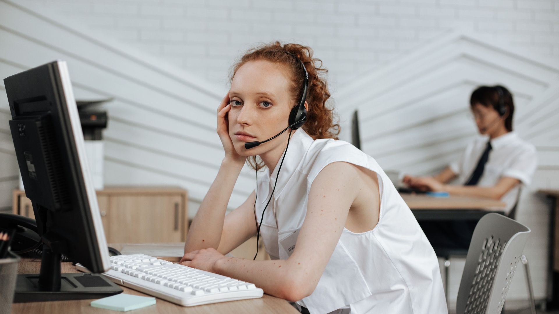 Focused call center agent with headset working at a modern office desk.