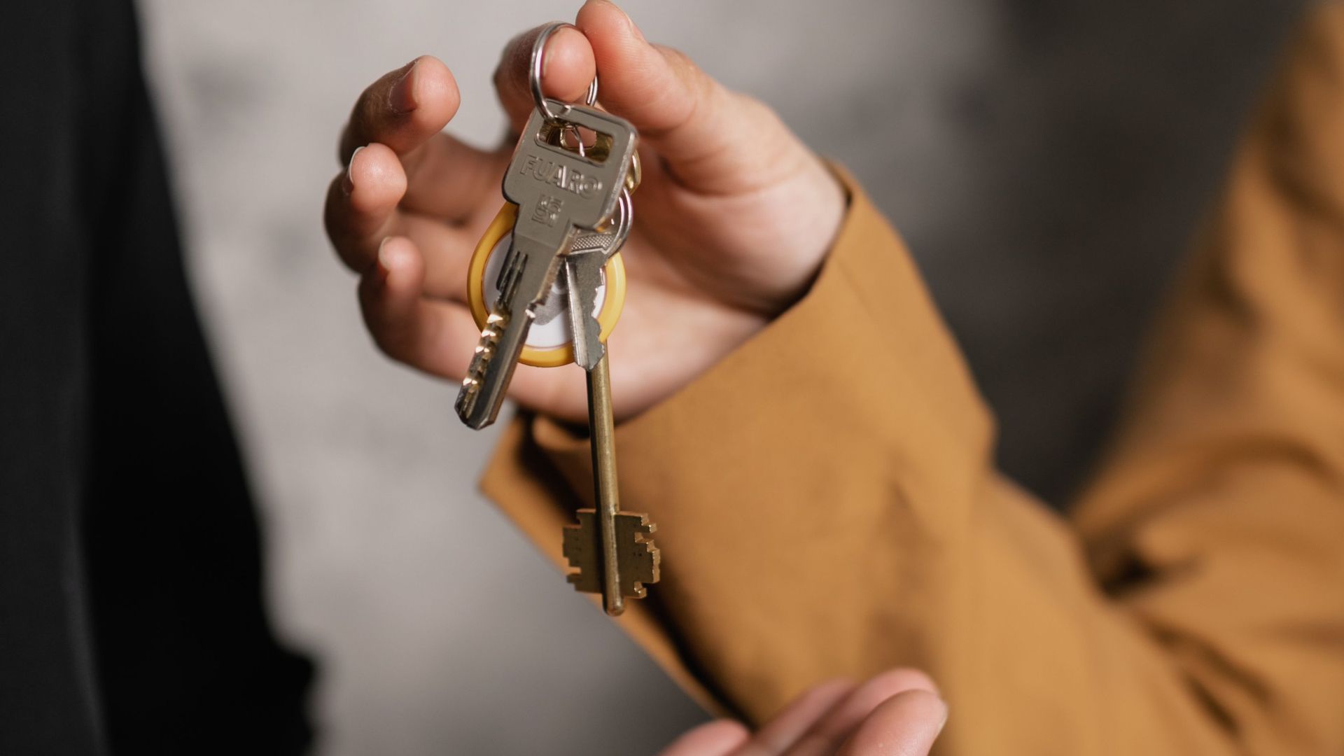 Two adults exchanging house keys, symbolic of property transfer or rental agreement.