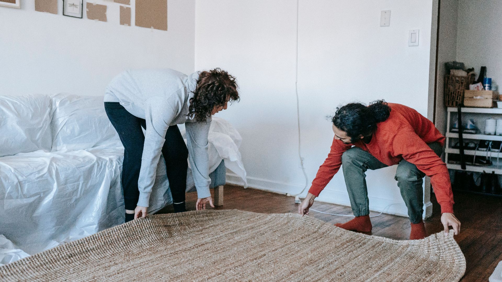 Couple arranging a rug in their contemporary apartment living room, teamwork concept.