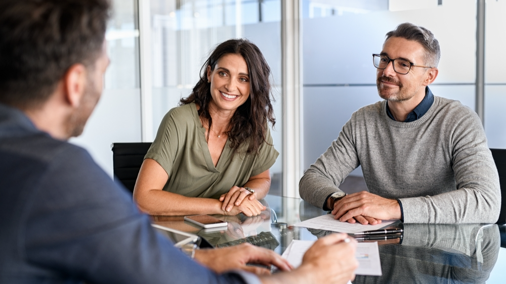 Smiling mature couple meeting with bank manager for investment