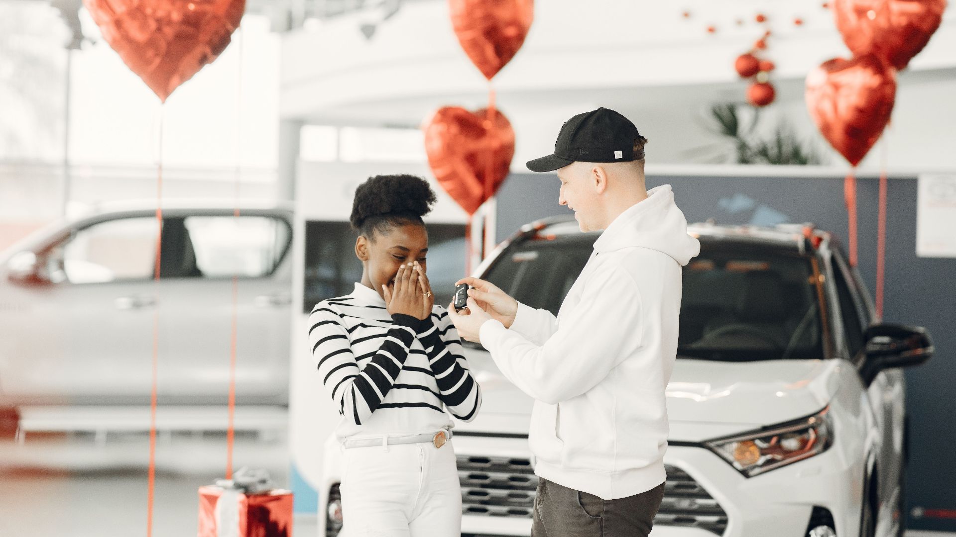 A joyful moment as a couple receives car keys in a decorated dealership.