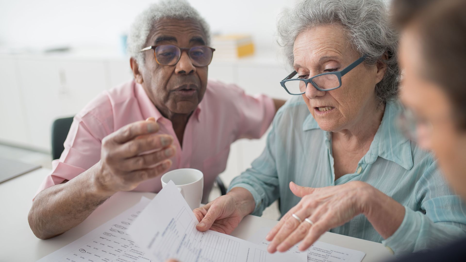 Elderly couple discussing financial documents with a consultant in an office setting.