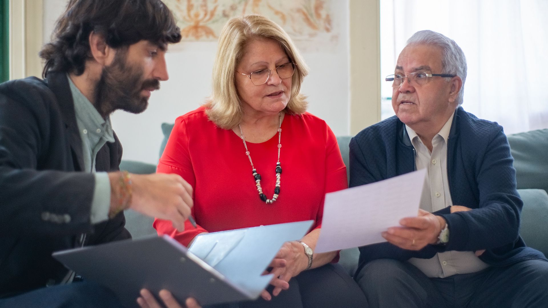 Senior couple consulting with a professional advisor, discussing documents indoors.