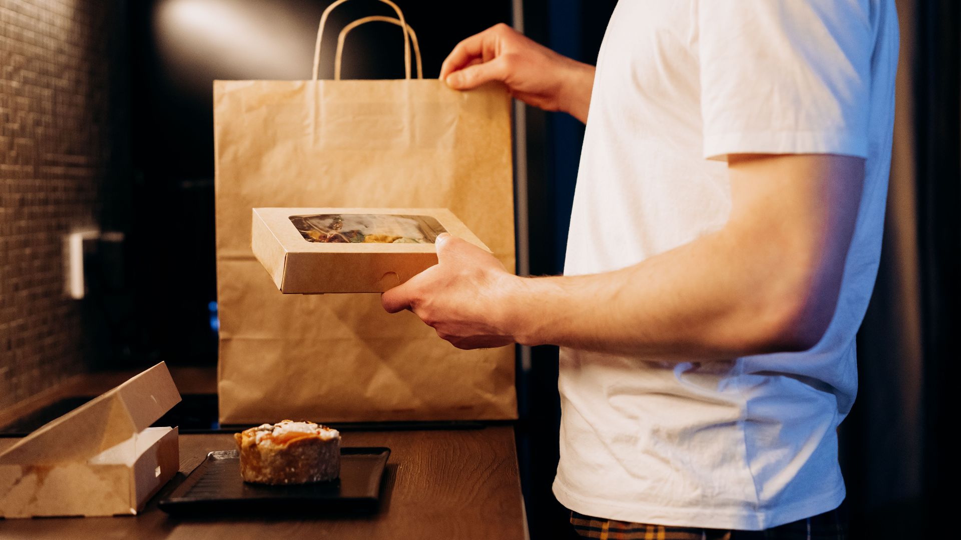 Man unpacking a food delivery bag in a modern kitchen. Ideal for lifestyle or delivery themes.