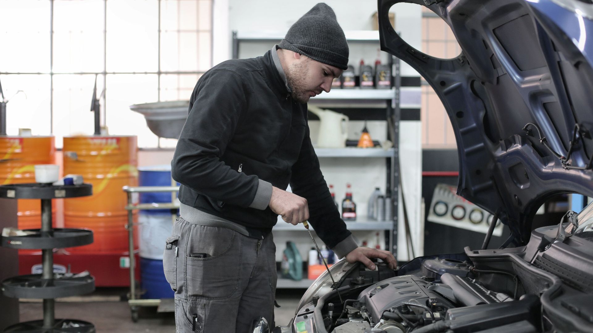 Mechanic checking a car engine in a garage, ensuring quality maintenance and repair.