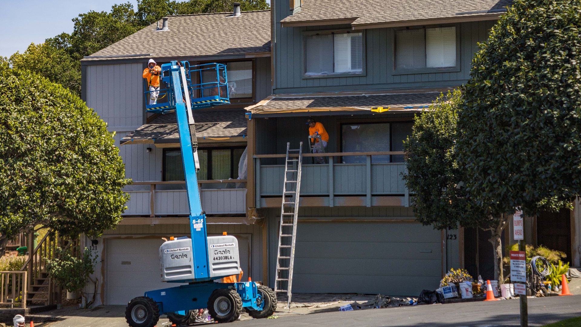 House being renovated with workers on a hydraulic lift in an urban area.