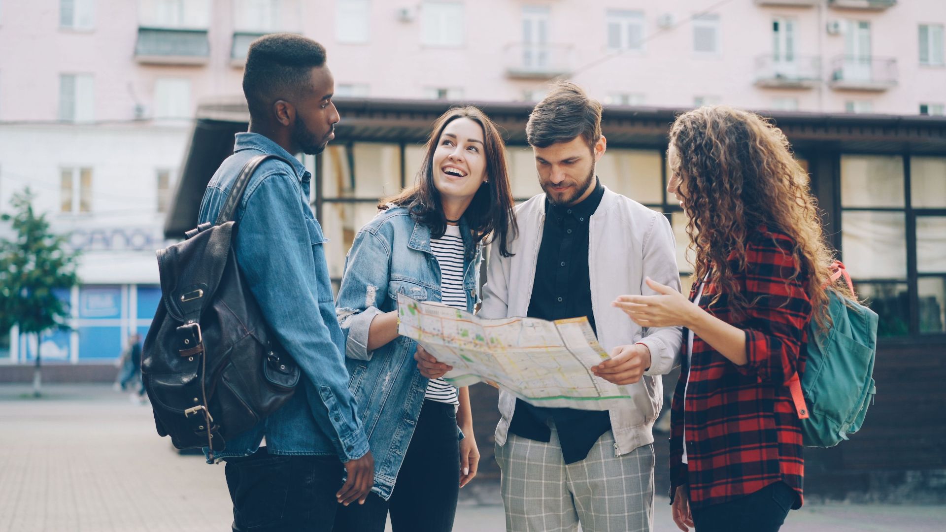 Four young friends reading a map outdoors, planning their city adventure.
