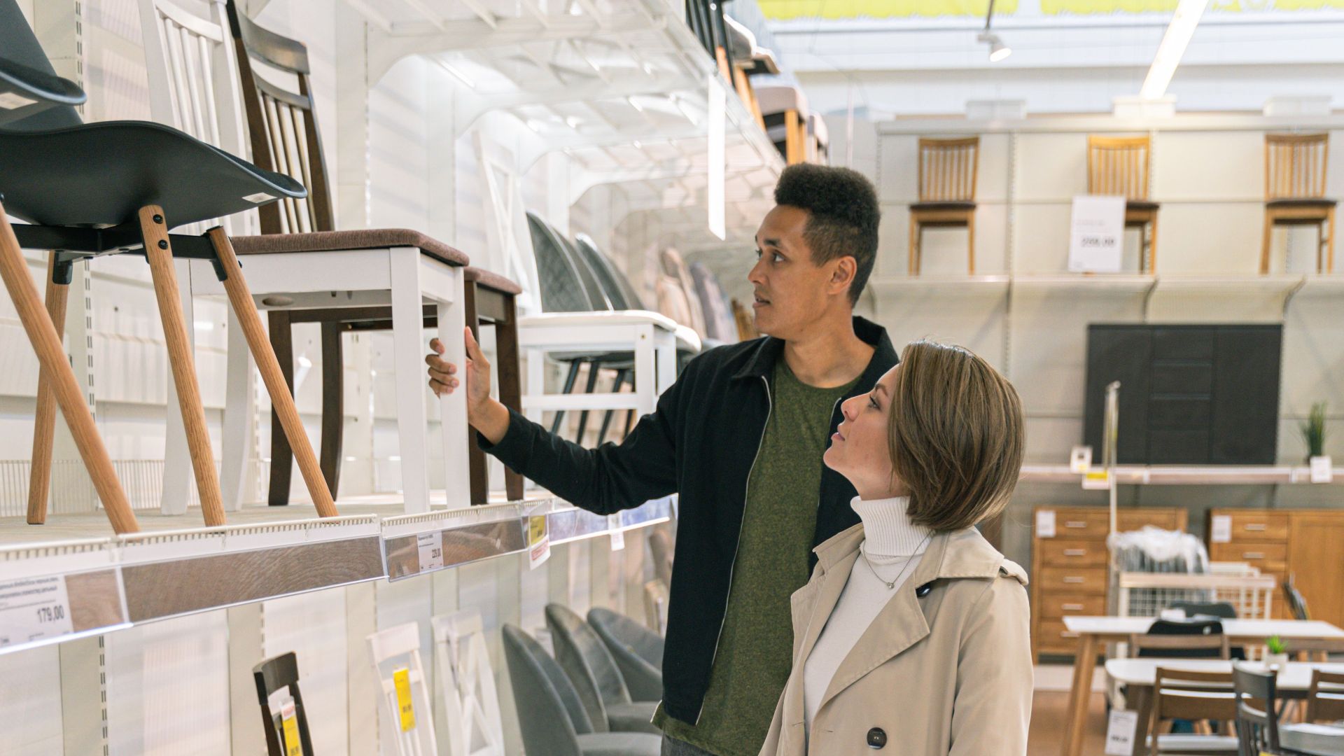 A couple browsing a selection of chairs in a well-lit modern furniture store.
