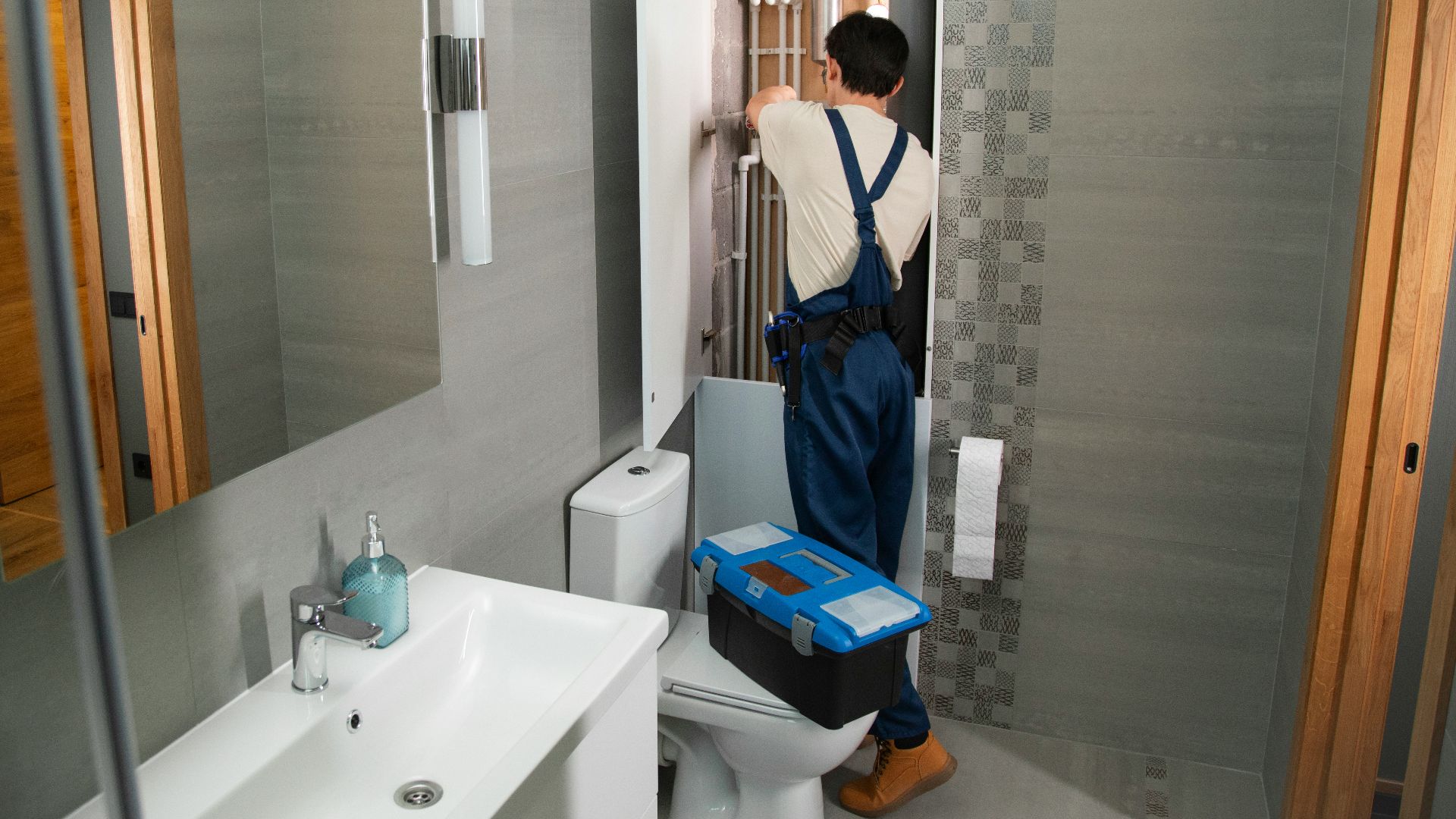 A plumber repairs plumbing in a bathroom