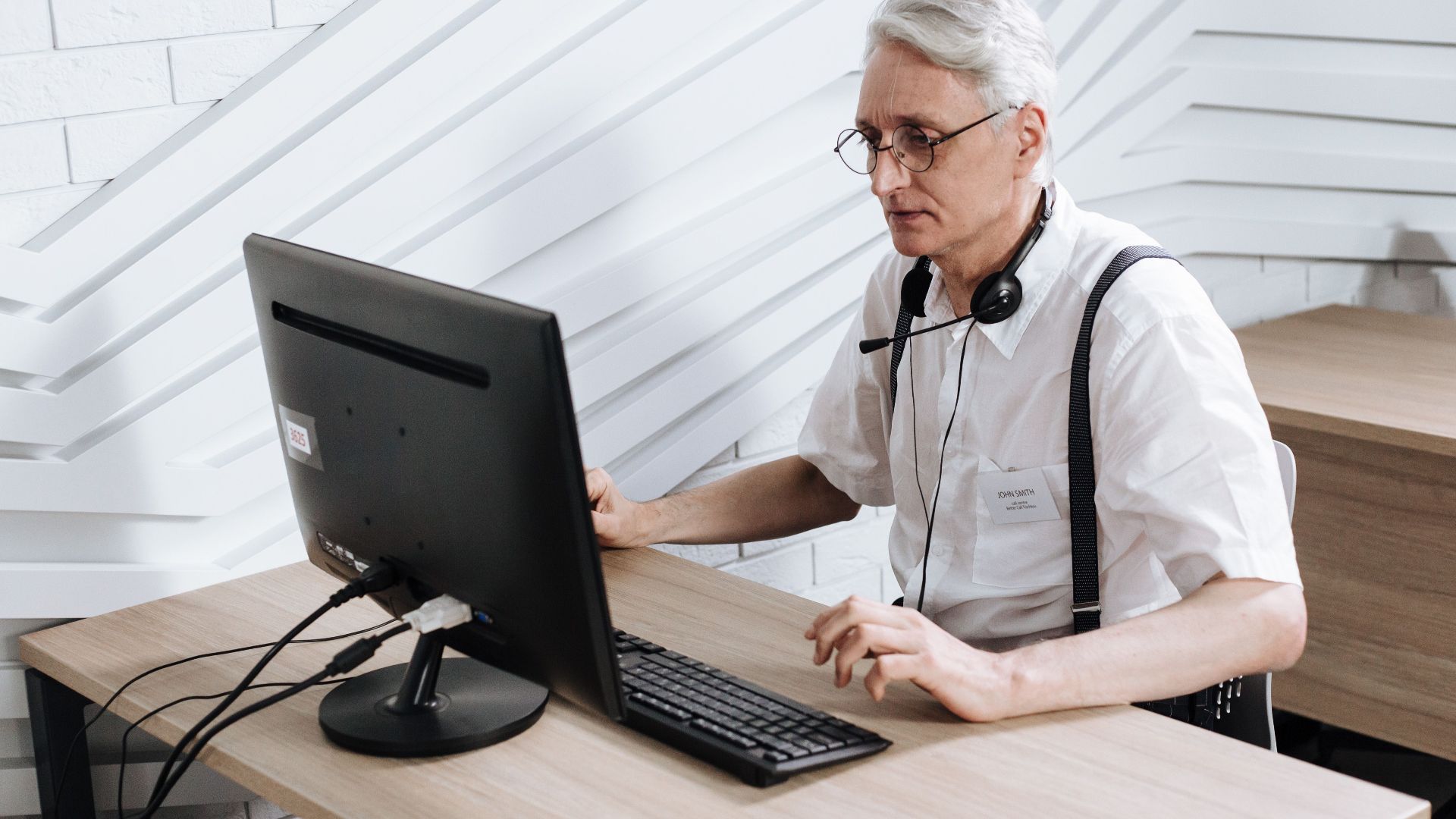 Senior adult man working in a call center with a headset and computer.