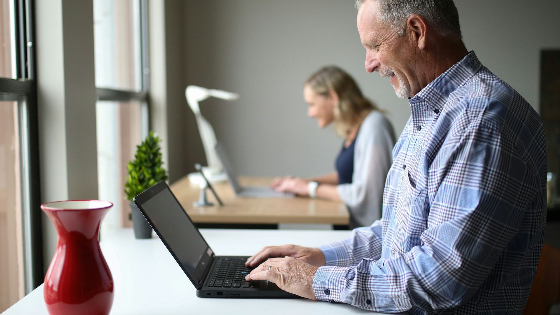 man in blue and white plaid dress shirt using black laptop computer