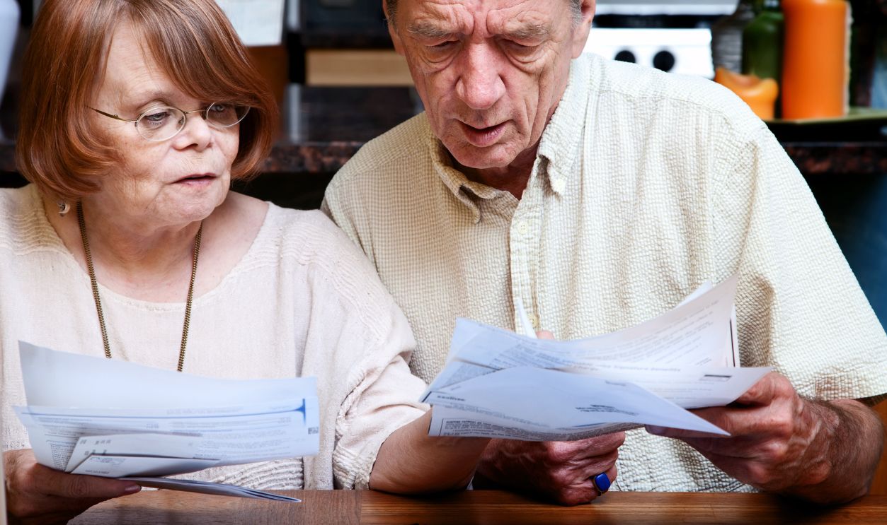 Senior couple at home organizing many bills