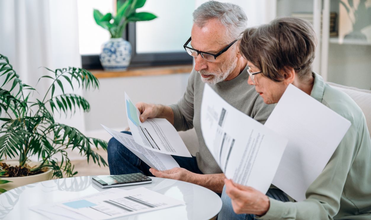 Elderly couple checking documents with tax and internal bills, making payments and discussing budget. Family calculating funds for purchase new home or car.