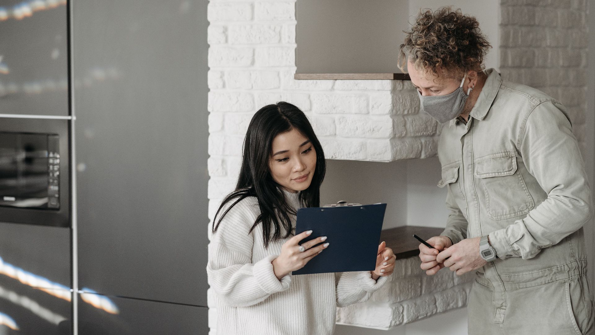 Masked courier and woman interacting indoors, highlighting safe delivery practices.