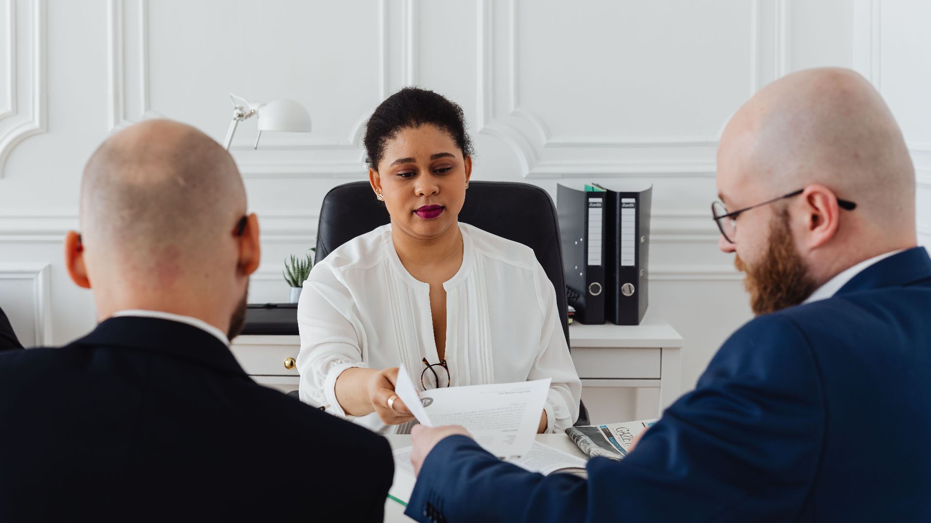 Business professionals in a serious meeting handing over a document.