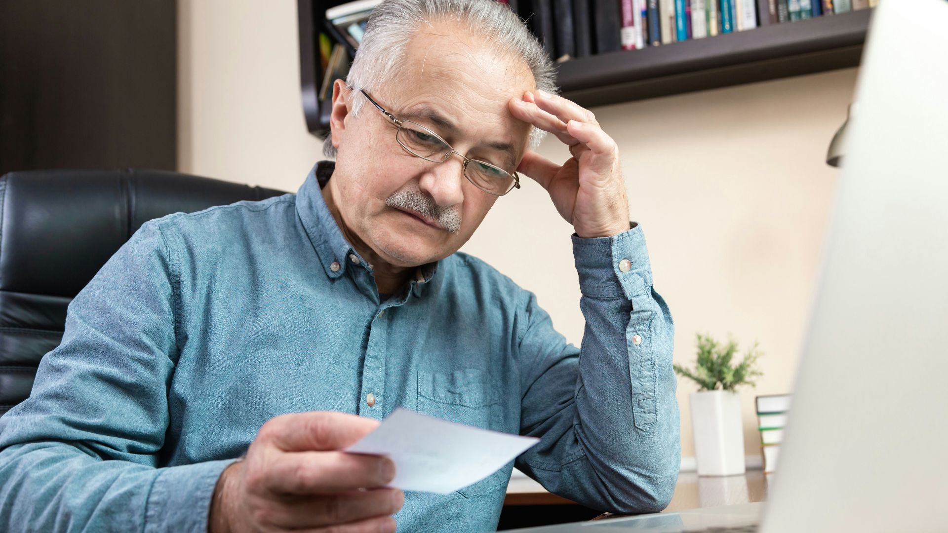 a man holding a pen and looking at a laptop