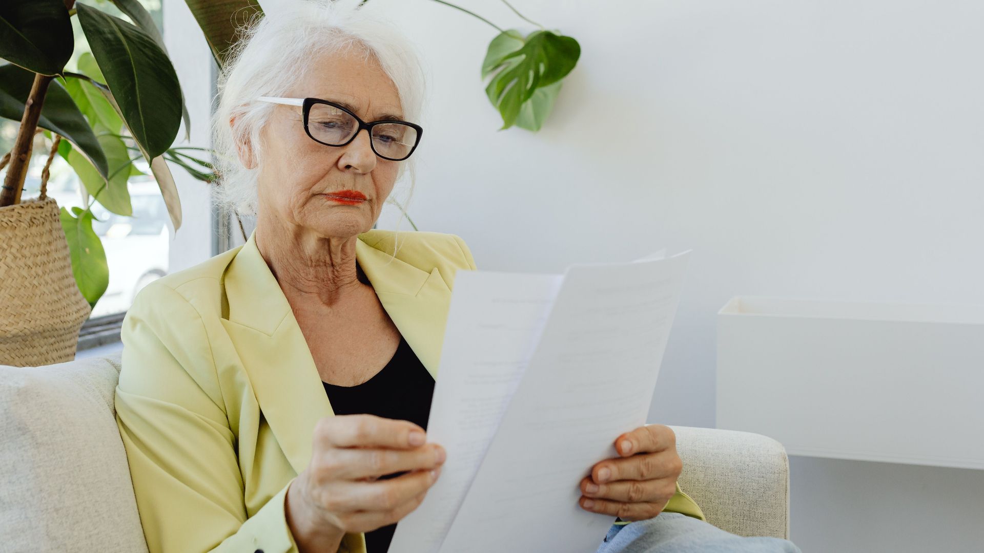 Portrait of a senior businesswoman in a blazer reading documents indoors.