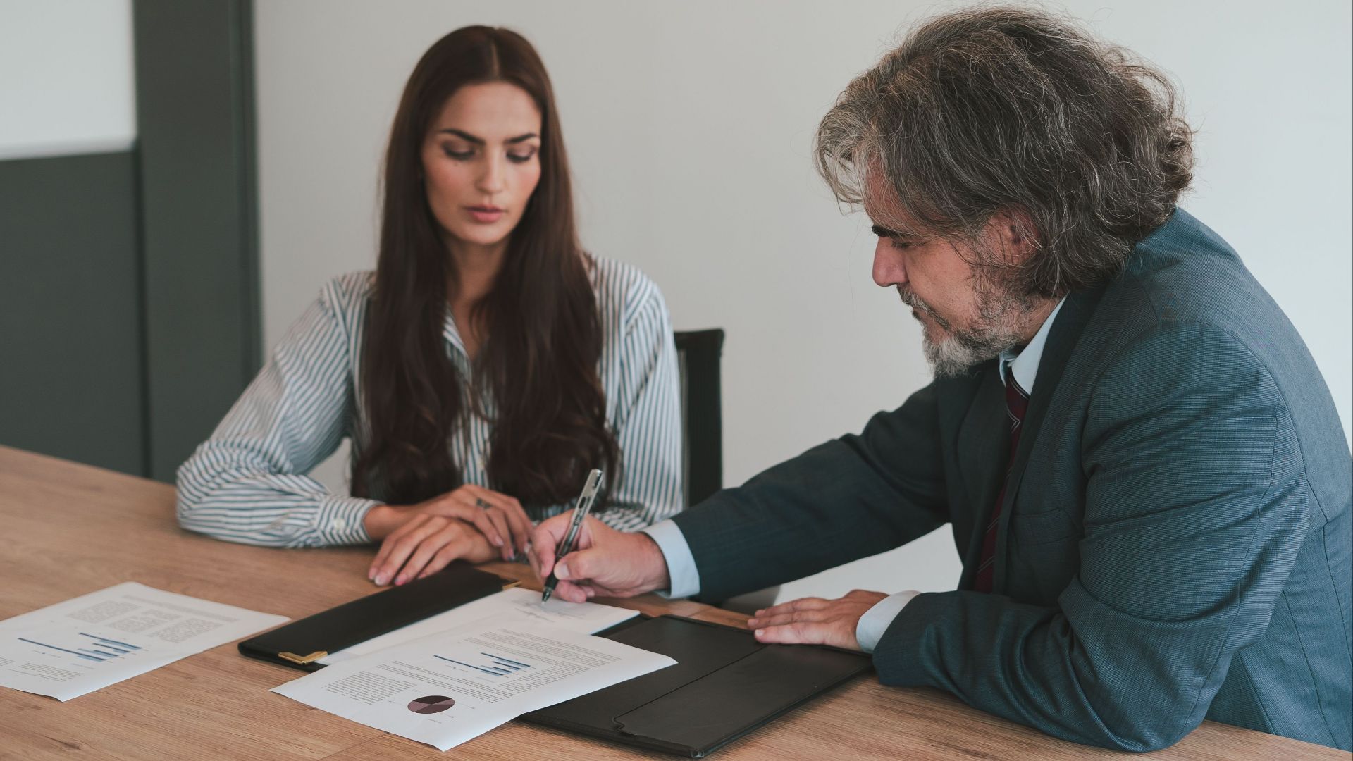 Professional business meeting with two colleagues reviewing documents at an office desk.